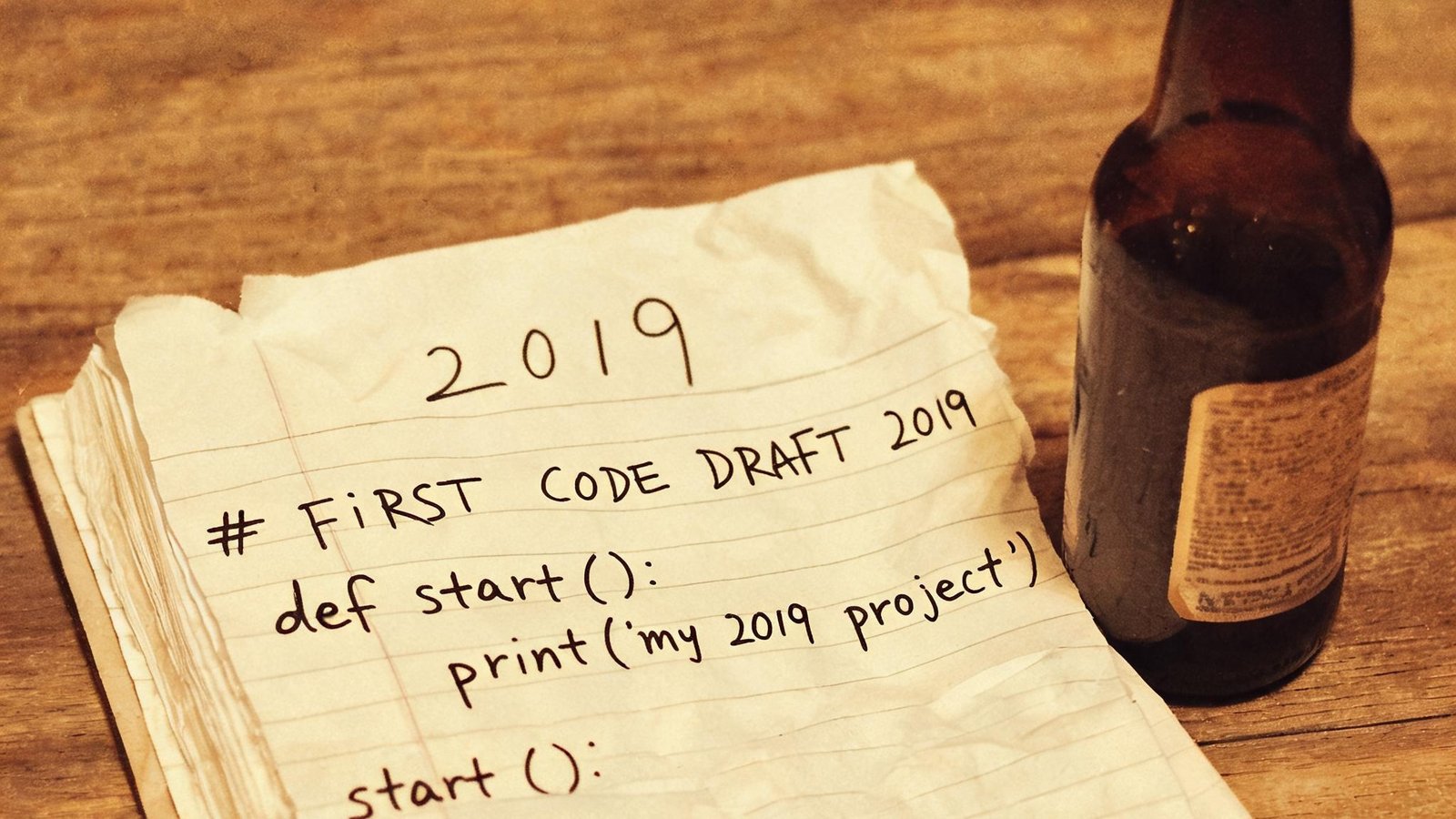 一张老照片：2019年最初的代码草稿写在皱巴巴的笔记本上，旁边放着啤酒瓶